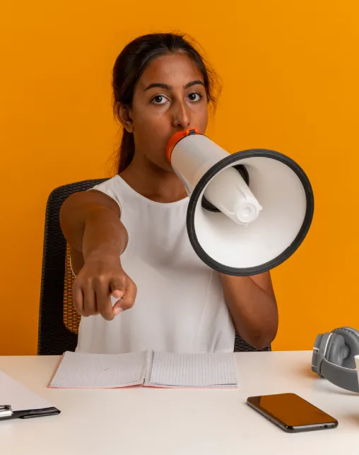 young-schoolgirl-sitting-desk-with-school-tools-speaks-loudspeaker